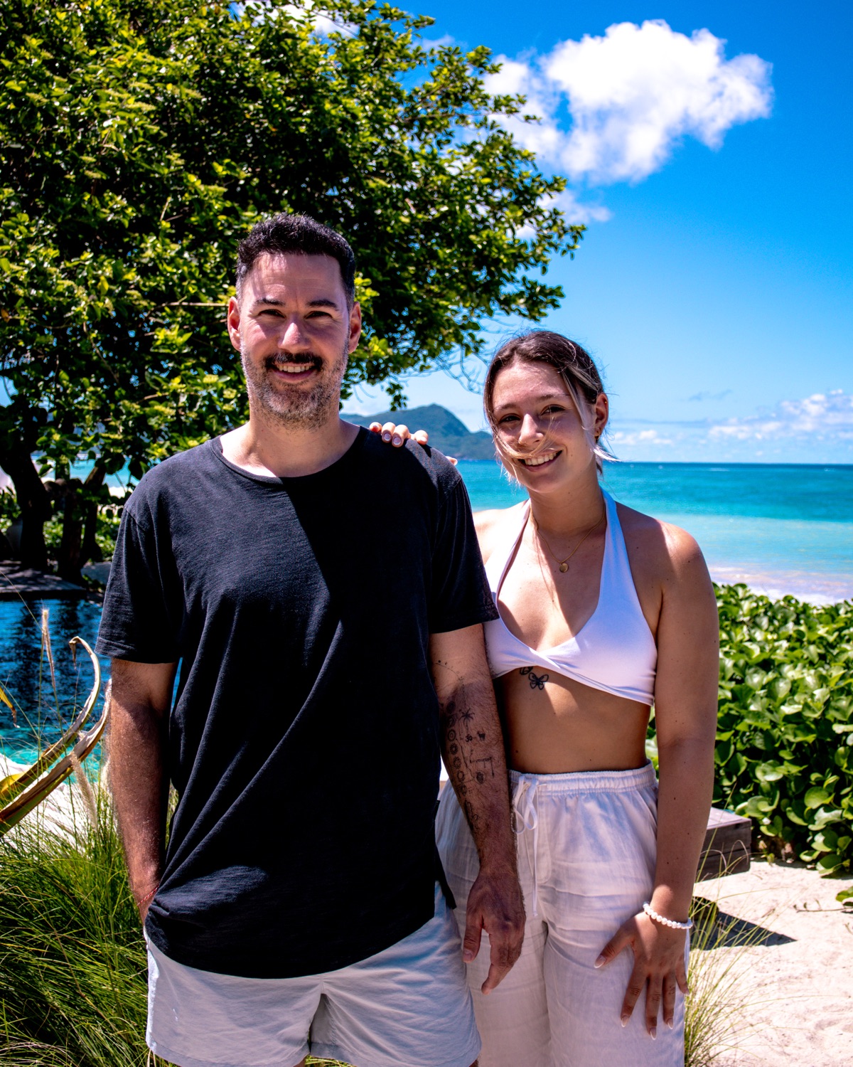 Daniel und Feli sitzen lachend vor türkisblauem Meer